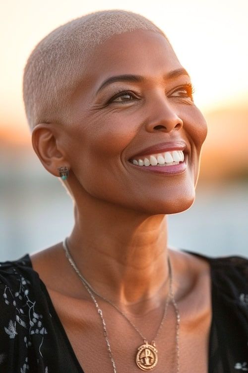 Corte de pelo rubio en una mujer negra de unos 50 años, sentada al aire libre durante la puesta de sol.