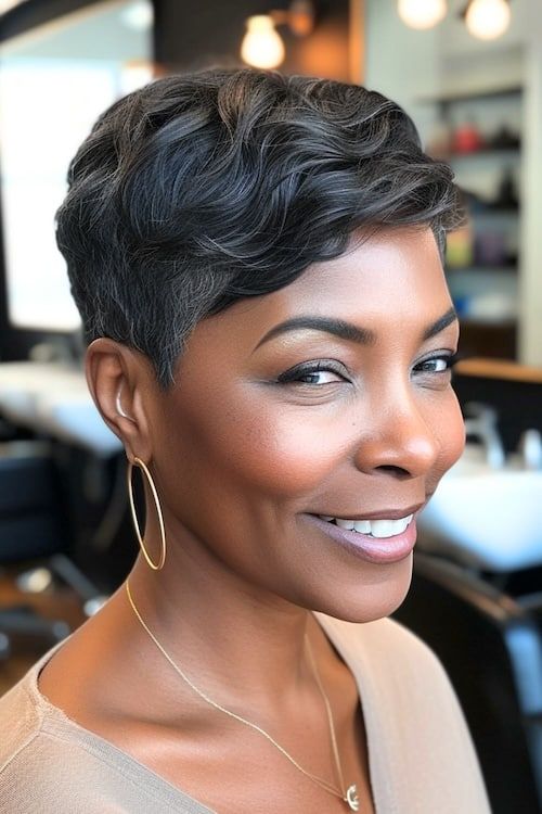 Corte pixie ondulado con lados afilados en mujer negra mayor en peluquería.