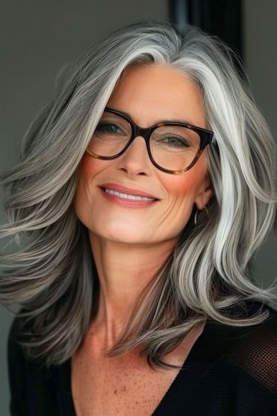Peinado con capas voluminosas para mujeres de más de 50 años con gafas.