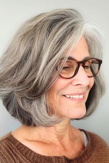 Peinado Bob a capas sal y pimienta para mujeres de más de 70 años con gafas.