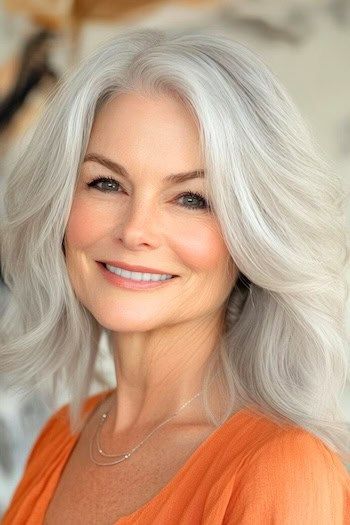 Peinado con ondas de longitud media en una mujer sonriente de unos 60 años con el pelo gris plateado.