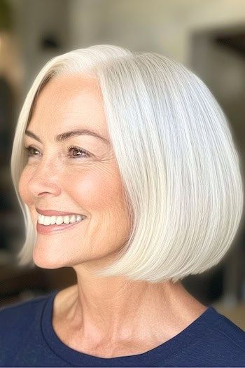 Elegante peinado Bob largo hasta la barbilla en una mujer sonriente de unos 70 años con el pelo blanco grisáceo, vista lateral.