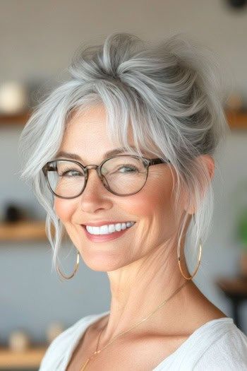 Peinado recogido despeinado en una mujer sonriente de unos 50 años con el pelo gris y gafas.
