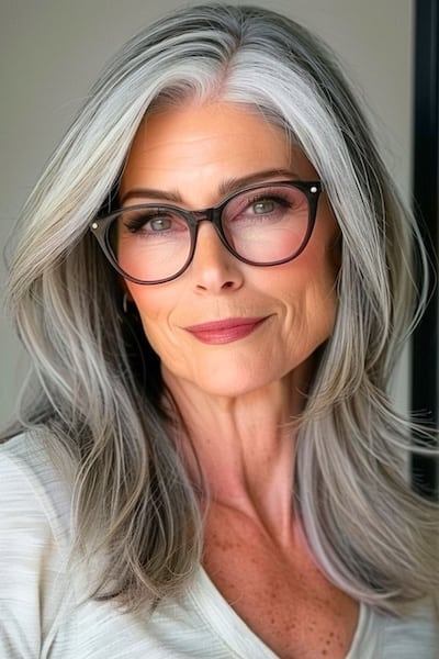 Peinado de capas largas con textura para mujeres de más de 50 años con gafas.